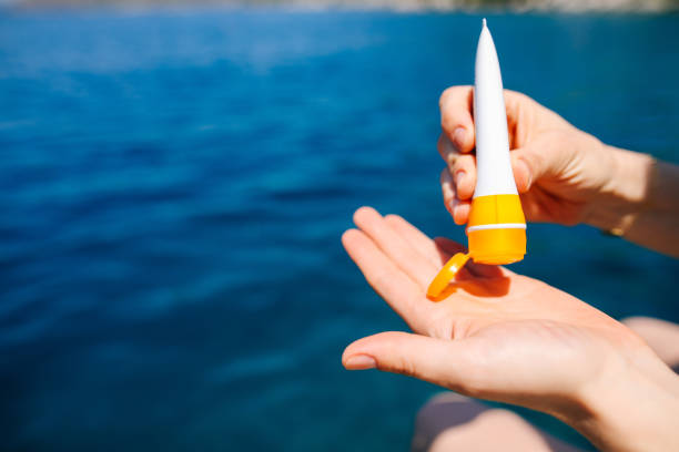 Woman hand apply sunscreen on the beach