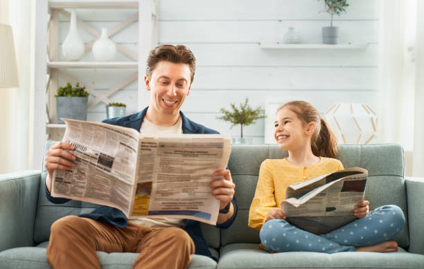 Happy father's day Happy loving family. Daddy and his daughter child girl are reading newspapers together. Father's day concept. reading newspaper stock pictures, royalty-free photos & images