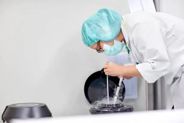 Side view of scientist handling oocytes and sperm for cryopreservation to be stored in liquid nitrogen.