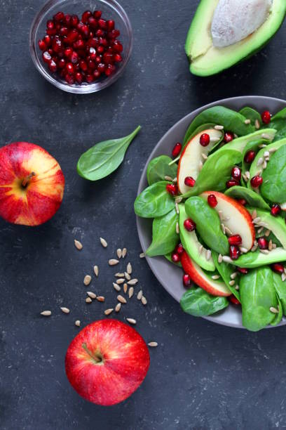 istock Fresh salad with spinach, avocado, apple, pomegranate and sunflowers seed on dark background. 1152441278