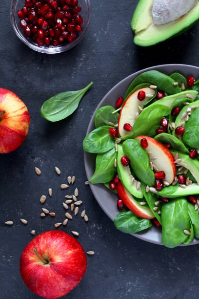 istock Fresh salad with spinach, avocado, apple, pomegranate and sunflowers seed on dark background. 1152441455