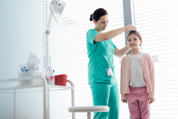 Nurse measuring height of girl against window at examination room Nurse measuring height of girl against window at examination room human height stock pictures, royalty-free photos & images