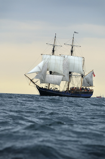 Tall ship sailing into the sunset with sails down. Off the coast of Cornwall, uk