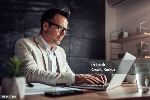 Businessman Sitting At His Desk And Using Laptop In The Office Stock Photo - Download Image Now