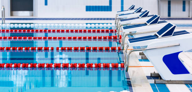 istock Swimming pool with marked red and white lanes. Empty swimming pool without people with quiet standing water. Water sports in indoor pool. 1152451302