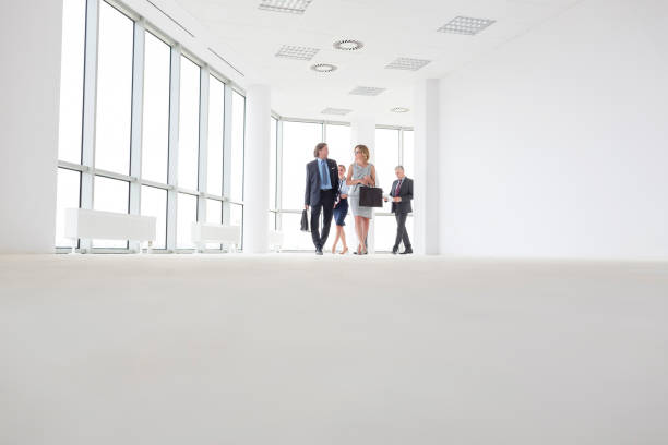 istock Full length of colleagues talking while walking in corridor at office 1152456358