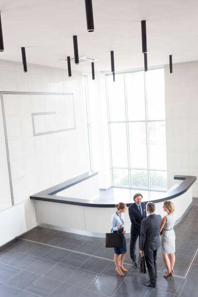 istock Businessmen greeting while standing with colleagues at reception lobby in new office 1152456443