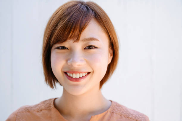 カメラで微笑む魅力的な日本人女性のポートレート - 正面から見た図 ストックフォトと画像