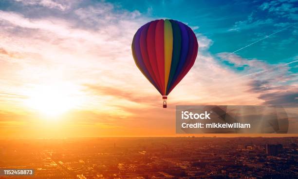 Hot Air Ballon Travels Above The City As Sun Sets In The Horizon Stock Photo - Download Image Now