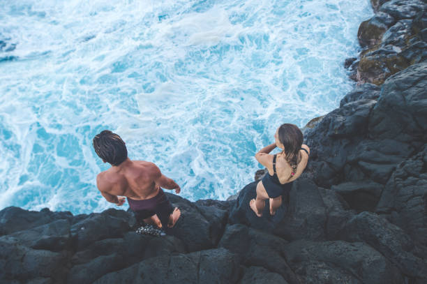 una pareja de edad milenario preparándose para saltar al océano - salto desde acantilado fotografías e imágenes de stock