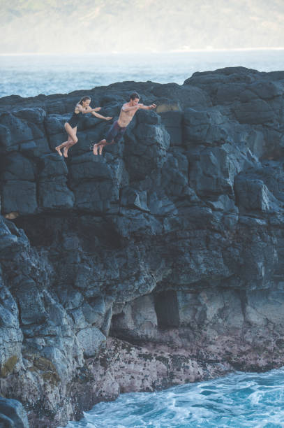 istock Couple jumping off a rocky cliff into the ocean for fun 1152466513