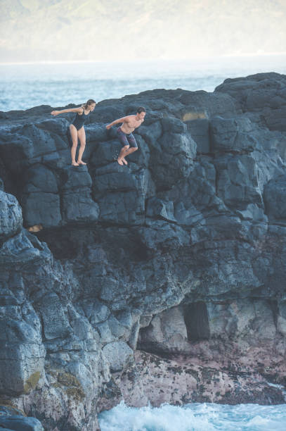 istock Couple jumping off a rocky cliff into the ocean for fun 1152466519
