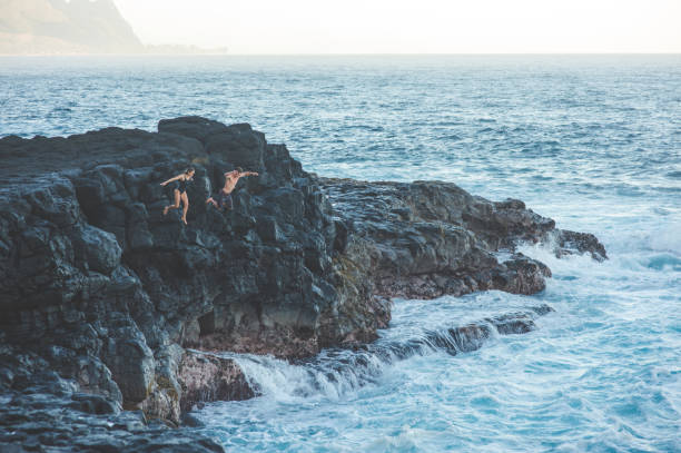 istock Couple jumping off a rocky cliff into the ocean for fun 1152466565