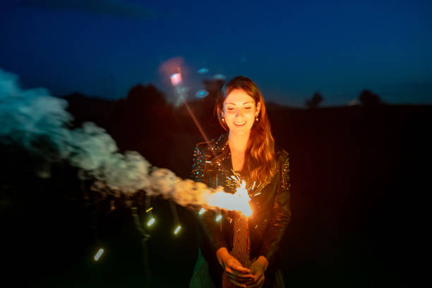 Woman holding a sparkler at night and wearing a black leather jacket.