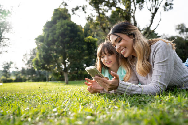 mère et fille au parc regardant des vidéos en ligne - rural watch photos et images de collection