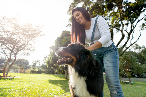 Happy Latin American pregnant woman walking her dog at the park â lifestyle concepts