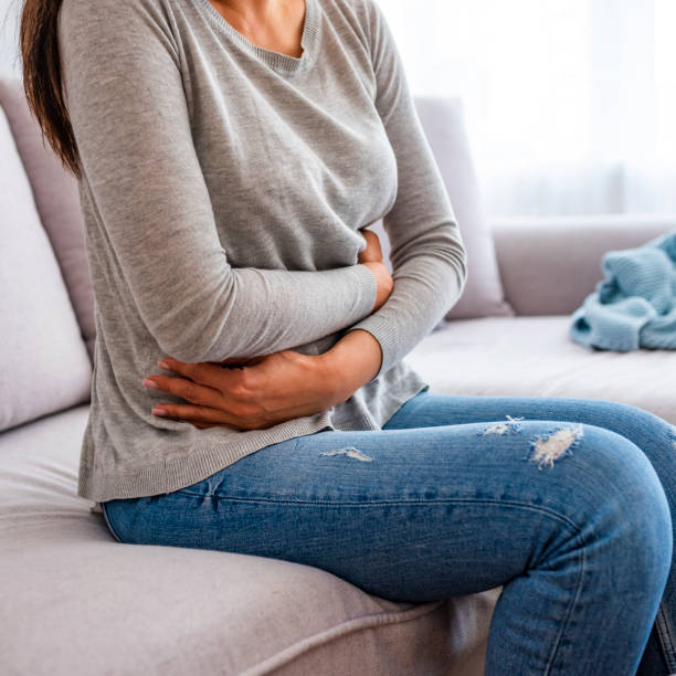 istock Young woman suffering from abdominal pain while sitting on bed at home. 1152474413