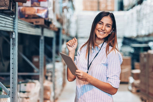 倉庫にデジタルタブレットを持っている笑顔の女性 - warehouse manager place of work portrait ストックフォトと画像