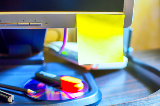 Yellow sticky note on wooden desk office computer screen, it's useful for business purposes.