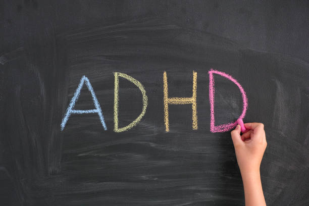 child writing abbreviation adhd on a blackboard - behavioral problems imagens e fotografias de stock