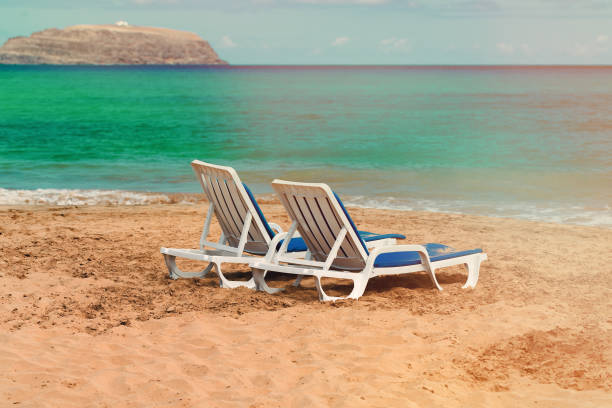 istock Two empty deck chairs on a deserted sandy beach on the ocean 1152486913