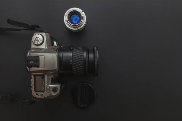 istock Photographer workplace with dslr camera system and lens on dark black table background. Hobby travel photography concept 1152487321