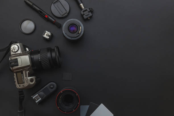 istock Photographer workplace with dslr camera system, camera cleaning kit, lens and camera accessory on dark black table background 1152487399