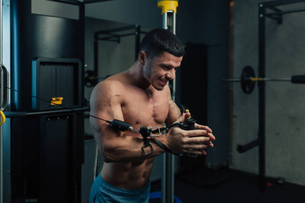Young strong man in gym doing chest cable workout Young strong man in gym doing chest cable workout with high intensity chest exercise cable RIPL Fitness
