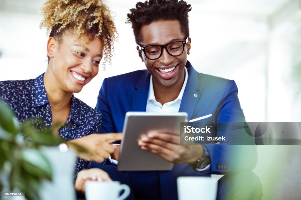 Smiling entrepreneurs looking at digital tablet Smiling entrepreneurs looking at digital tablet. Happy corporate workers are working on online investment plans. They are related to financial occupation. 30-34 Years Stock Photo