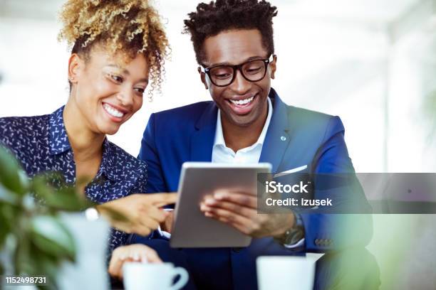 Smiling Entrepreneurs Looking At Digital Tablet Stock Photo - Download Image Now - 30-34 Years, Adult, Adults Only