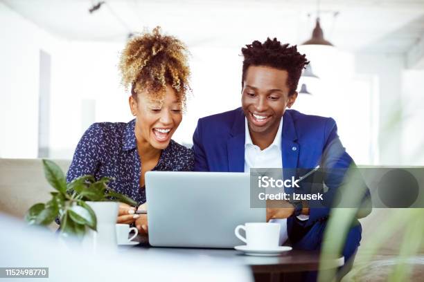 Happy Professionals Looking At Laptop In Office Stock Photo - Download Image Now - African-American Ethnicity, Financial Occupation, 30-34 Years