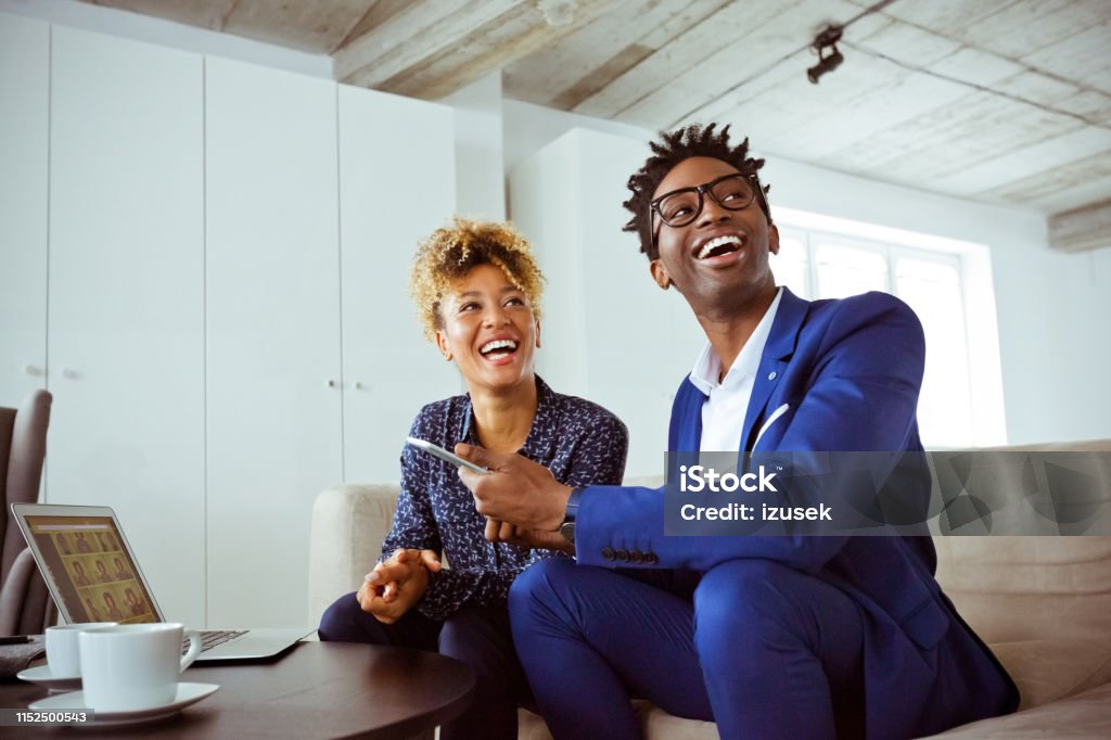 Cheerful financial advisors looking away on sofa Cheerful financial advisors looking away while sitting on sofa. Skilled corporate workers are working in team. They are wearing formals in office. Financial Advisor Stock Photo