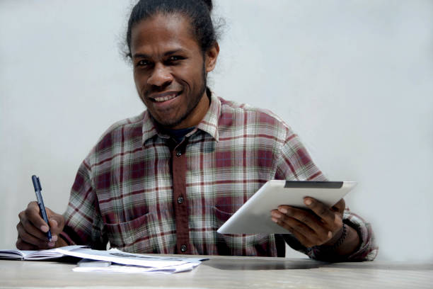 istock a young black man working and studying holding laptop and pen doing homework 1152504701