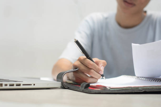 istock close up with hand doing home work with pen and laptop 1152505038