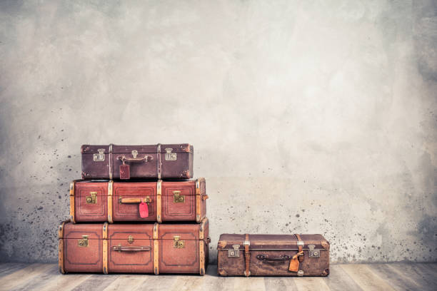 vintage classic outdated trunks luggage with tags, old antique leather suitcases front textured aged concrete wall background. travel baggage concept. retro style filtered photo - trunk luggage old fashioned retro revival imagens e fotografias de stock