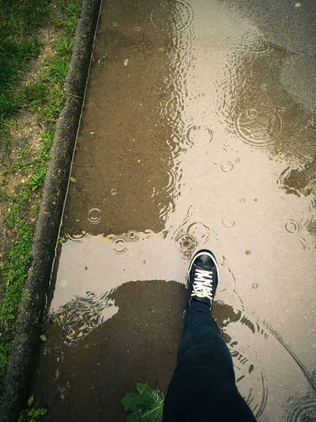 istock a woman walks on a puddle on a sidewalk 1152508162