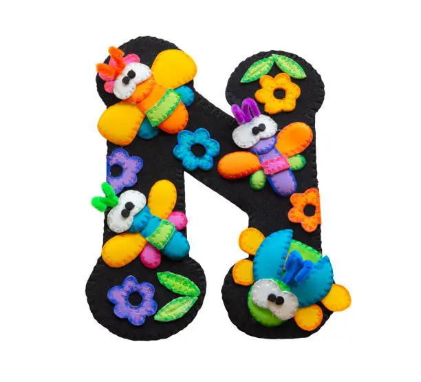 Photo of Letter N made in black foamy decorated with toy butterflies made in foamy and blue, yellow and orange flowers