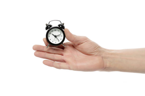 istock Male hand holds a clock shows the time on a white isolated background. 1152512670