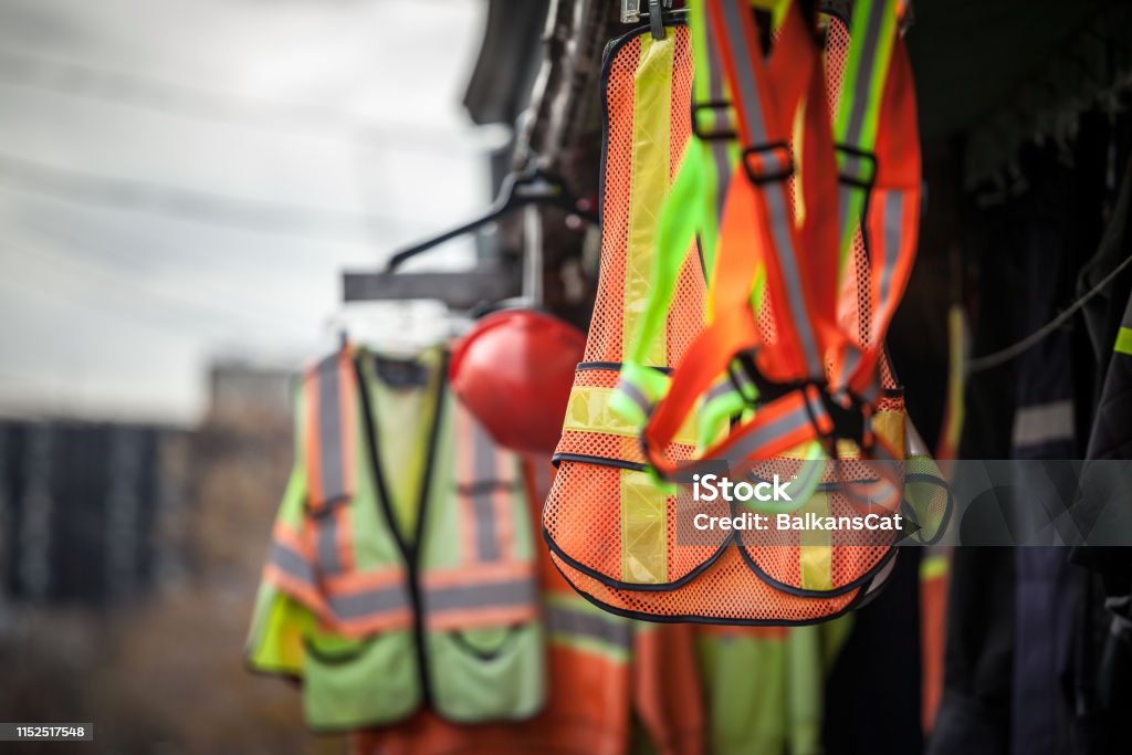 Personal protective equipments for sale on a shop: harness, reflective vests, yellow jackets, construction site helmets, as well as various other PPE devices Picture of PPE, or personal protective devices, for sale in a shop, haning. Yellow and Orange vests, harnesses and helmets are visible Safety Stock Photo