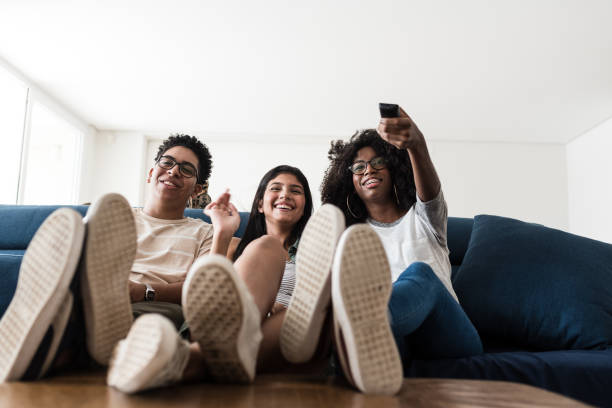 adolescentes que sentam-se no sofá que escolhe o filme junto - sentar se pose - fotografias e filmes do acervo