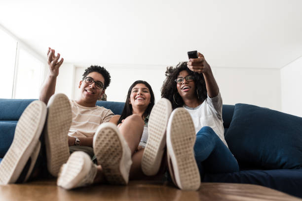 adolescentes que sentam-se no sofá que escolhe o filme junto - sentar se pose - fotografias e filmes do acervo