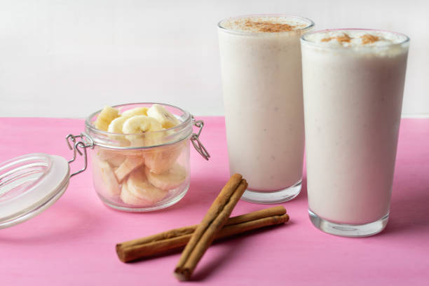 istock Banana smothie or milkshake with cinnamon on pink  background 1152520643