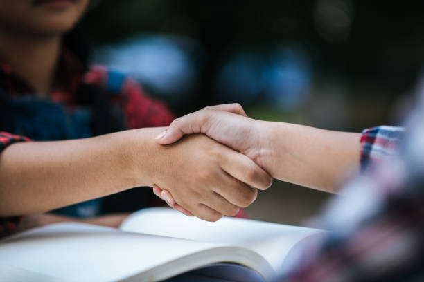 mädchen college-studentin schütteln hand ihre freundin im college-park - greeting teenager handshake men stock-fotos und bilder
