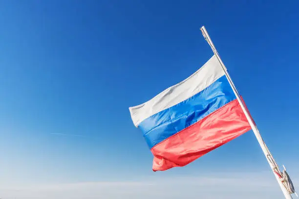 Russian tricolor develops in the wind in a clear sky