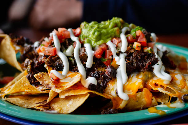 Beef and cheese corn nachos served on a big plate ready to eat Beef and cheese corn nachos served on a big plate ready to eat - Image nacho chip stock pictures, royalty-free photos & images