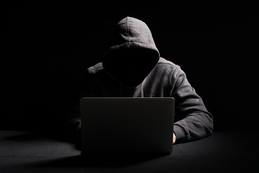 Hacker trabajando en el ordenador portátil en la oscuridad photo