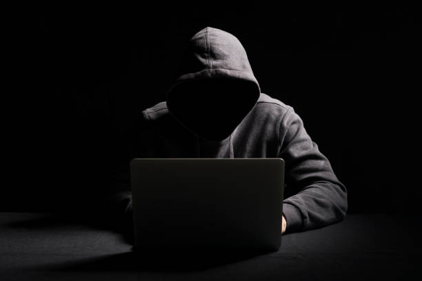 hacker working on laptop in the dark - computer hacker computer crime computer thief imagens e fotografias de stock
