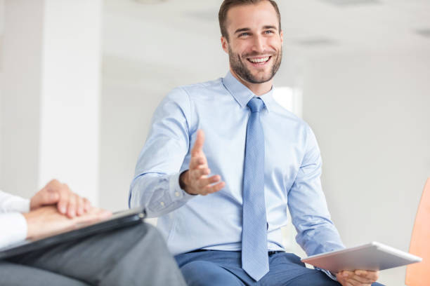 istock Smiling young businessman gesturing while sitting at office during meeting 1152537958