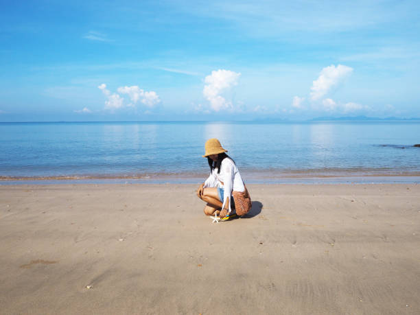 Asian woman and starfish on summer beach background. Holiday vacation concept.
