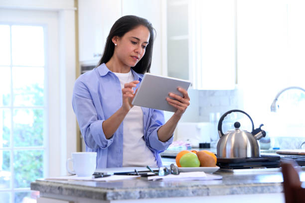 istock A Latina Millennial Working On Her Digital Tablet In Her Kitchen 1152538970